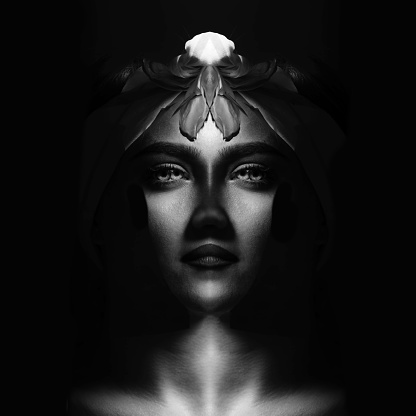 Abstract, fine art, sci-fi concept. Abstract and futuristic looking woman portrait. Alien or extraterrestrial looking model with hair, eyes and lips looking calmly at camera. Black and white image