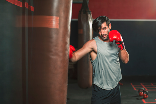 Sport man Young athletic man doing punching sandbags boxing. Muscular and strong guy exercising .