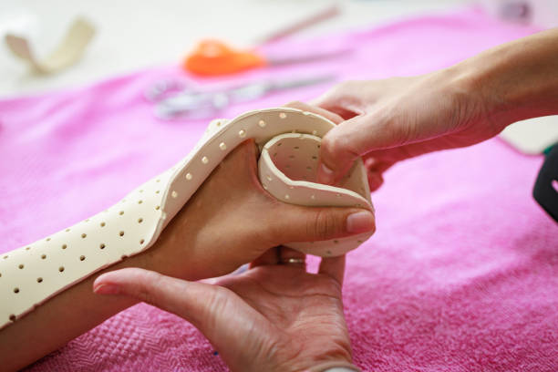 Therapist making assistive device for immobilize patient hand. Splint service for hand injury rehabilitation of occupational therapy clinic.