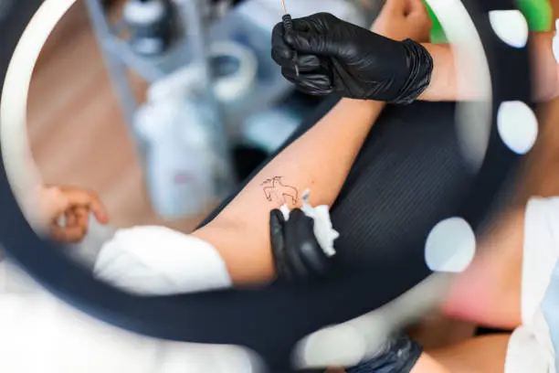 Photo of Tattoo mater tattooing dove of peace on woman's hand