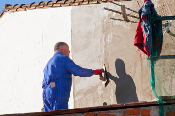 Construction worker applying plaster on building facade stock photo