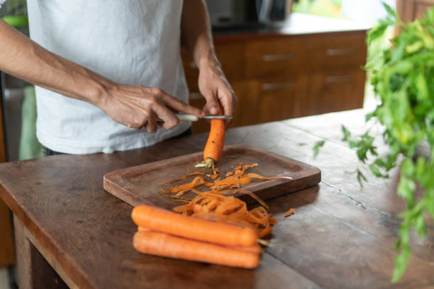 istock Young man peeling carrots in his kitchen 1433624640