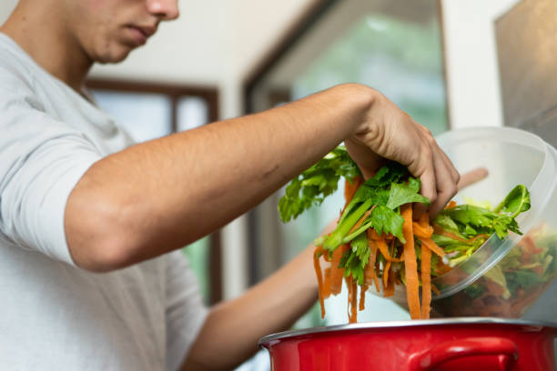 Young man making vegetable soup, broth, out of vegetable scraps