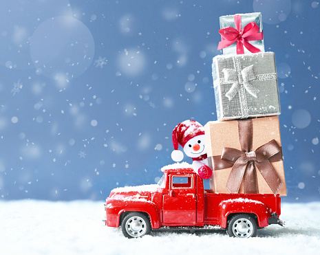 Christmas background with snow, snowman and retro red car with gift box. .Merry Christmas and happy New Year greeting winter card with copy-space