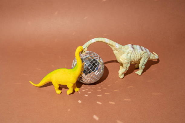 istock Two dinosaurs with disco ball on a brown background. Plastic toys. Minimal design. 1433631102