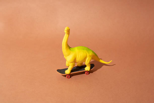 istock Plastic toy dinosaur standing on a skateboard. Brown background. Minimal design. 1433631104
