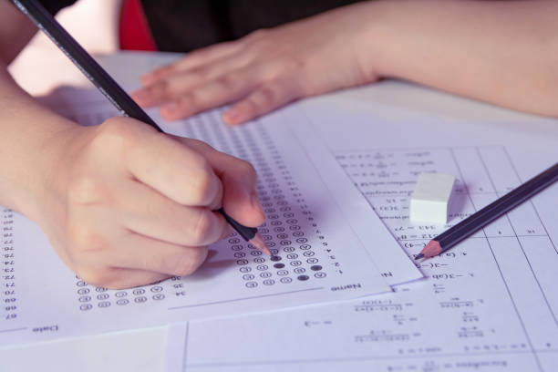 istock Students hand holding pencil writing selected choice on answer sheets 1433631808
