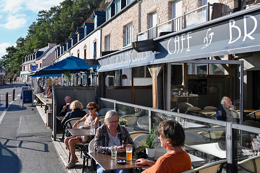 Erquy, France, September 18, 2022 - Tourists and locals enjoying summer weather in sidewalk cafes in Erquy harbor