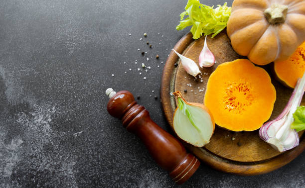 istock Vegetables: orange squash, garlic, onions. Spice mill, pepper, salt. Black background. Copy space 1433638956