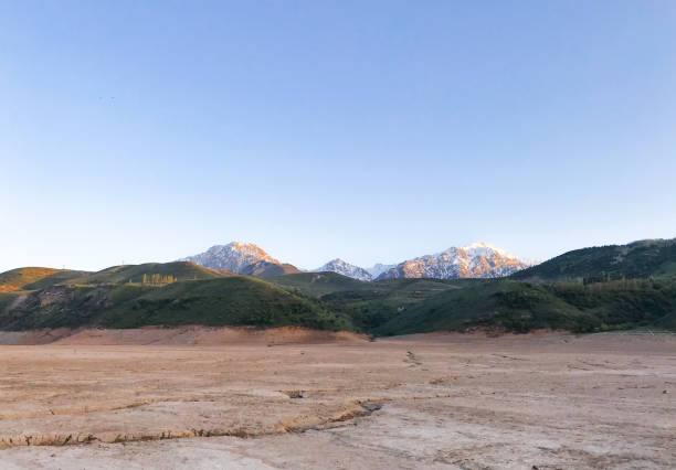 夕日のある美しい風景:山々、湖、石のあるひびの入った土 - 乾燥した川の曲がり角 - global warming drought riverbank dirt ストックフォトと画像