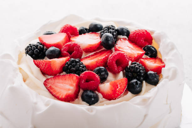 Pavlova meringue cake with fresh berries on white background