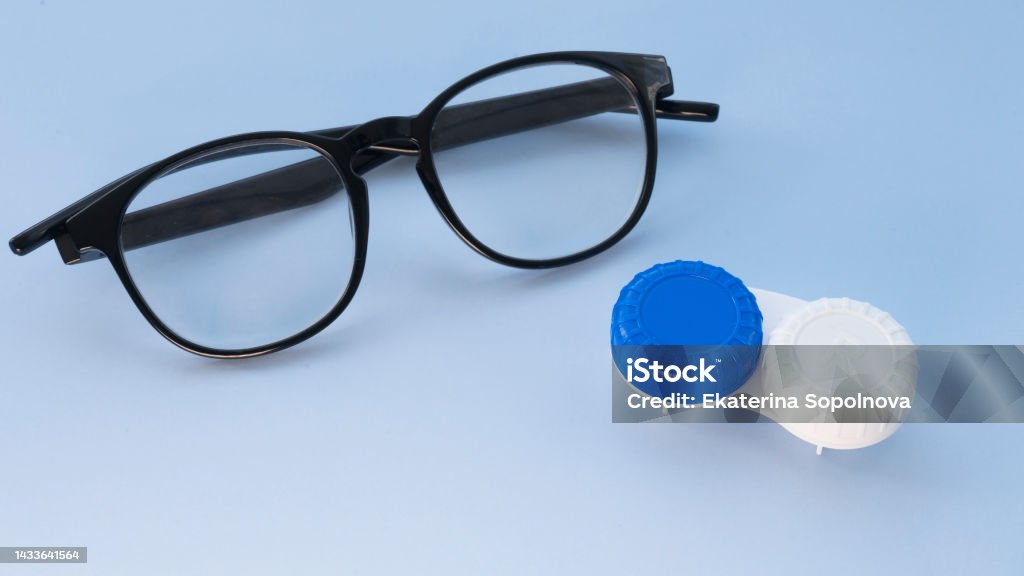 Glasses and container for contact lenses on a light blue background Contact Lens Stock Photo