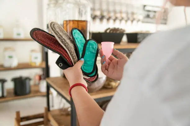 Photo of Woman comparing different reusable period products, pads and menstrual cups