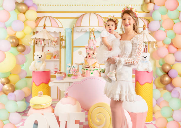 Beautiful little candy princess girl in crown holding big pink heart lollipop and smiling