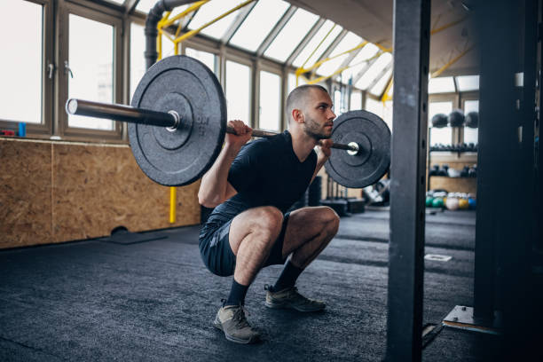 重み付きの男の訓練 - weight training crouching barbell weightlifting ストックフォトと画像
