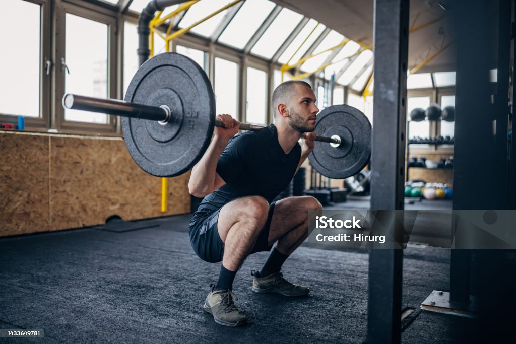 Man training with weights One man, fit young man training with weights in gym. Gym Stock Photo
