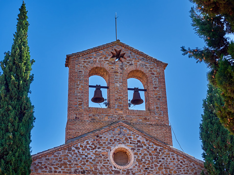 Stone and brick bell tower with two bells of the church  Parroquia de Nuestra Señora del Buen Consejo y San Anton. Puerto Lapice, a picturesque village in the route of Don Quixote, province of Ciudad Real, Castilla La Mancha, Spain, Europe