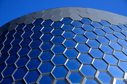 Honeycomb blue glass windows. Part of glazed facade of modern building. City space.