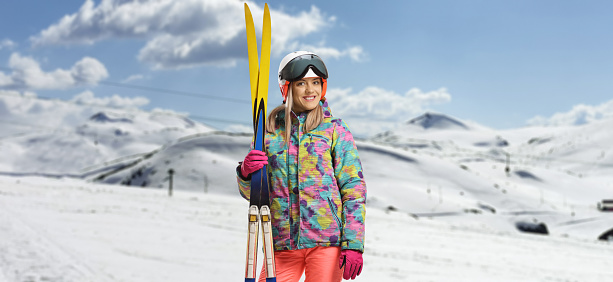 Excited female skier carrying skis on Souders with full equipment on. Winter and ski sports concept
