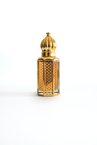 Arabian oud perfume in mini gold hexagonal bottle. Isolated on white background. Copy space.