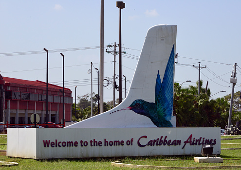 Port of Spain, Port of Spain, Trinidad island, Trinidad and Tobago: welcome sign outside Piarco International Airport, primary hub and operating base for the country's national airline, as well as the Caribbean's largest airline, Caribbean Airlines - vertical stabilizer with hummingbird