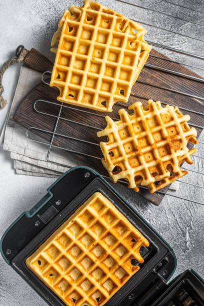 istock Cooking of fresh waffles in waffle maker. White background. Top view 1433657795