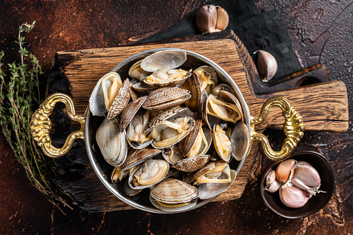 Garlic white wine shells Clams, vongole in a skillet with herbs. Dark background. Top view.
