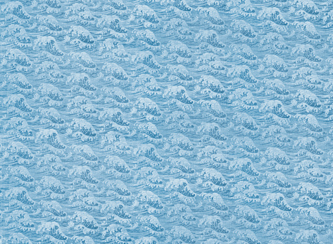 Photograph of highly detailed Japanese traditional wrapping cotton fabric called furoshiki featuring a seamless pattern of a blue sea wave like that of the famous hokusai and used for wrapping goods.