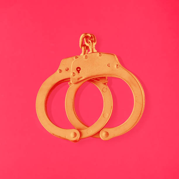 고립 된 활기찬 빨간색 배경에 황금 수갑을 잠근다. 다양성, 관용, 차이, 관계, lgbtq 또는 동성애 커플의 최소한의 사랑 질감 개념. 발렌타인 패턴. - golden handcuffs 뉴스 사진 이미지