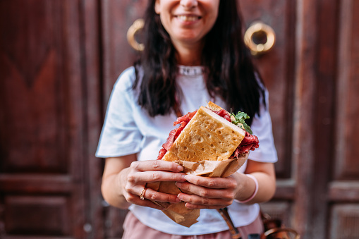 Woman holding homemade focaccia sandwich with ham