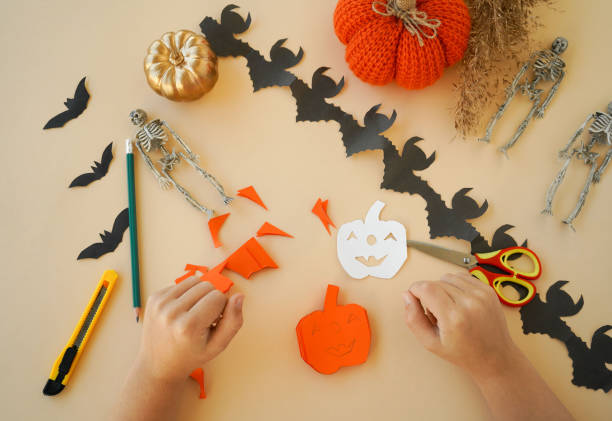 istock Step-by-step instructions for creating garlands of paper decorations by children for the Halloween holiday. Step 5 cut out with scissors or a stationery knife 1433673783