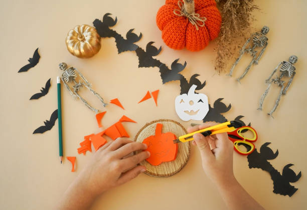istock Step-by-step instructions for creating garlands of paper decorations by children for the Halloween holiday. Step 5 cut out with scissors or a stationery knife 1433673785