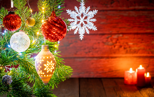 Christmas fir tree background with baubles, snowflake and glowing Christmas lights bokeh