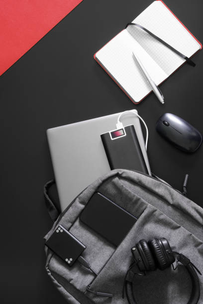 istock Urban backpack with laptop, external battery - power bank, mobile phone, external ssd memory, mouse, headphones, notepad and pen on black and red background. Study and travel with gadgets. 1433678322