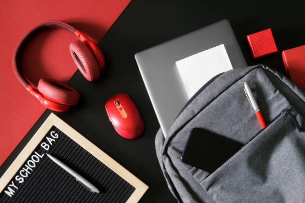 istock Gray urban backpack with laptop, pen, notepad and smartphone on a black and red next to headphones, mouse and the inscription my shool bag. Concept of portfolio modern schoolboy or student 1433678372
