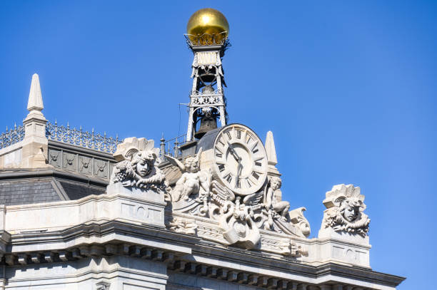 Madrid, Spain - September 25, 2022: Close-up of architectural detail on the upper part of a bank building. A bell tower with a golden ball is on top of the building.
