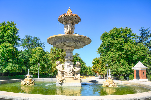Madrid, Spain - July 18, 2022: View of Artichoke Fountain with Triton and Nereida.  At the top of the fountain, some children are depicted standing under an actual artichoke.