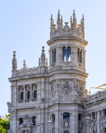 Madrid, Spain - July 18, 2022: Close-up view of the Facade of an old white building. The building has architectural details, a tower-like structure at the top, and no people are on the scene.