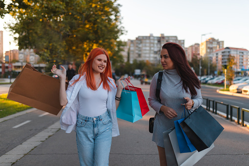 Two happy young women having fun while out shopping. They are in downtown.