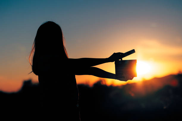 silhouette of a woman holding a cinema clapperboard in the sunset - atriz imagens e fotografias de stock