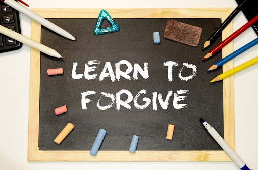 Text Learn to Forgive written with golden letters on a red heart