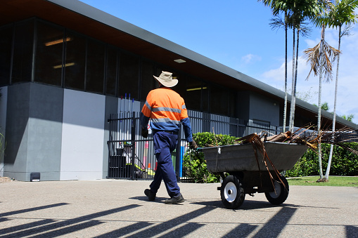 Mackay, Aus - Sep 28 2022:Australian Public municipal worker pulling a wheelbarrow.In Australia, blue-collar workers are predominantly male and form approximately 30% of the Australian workforce.