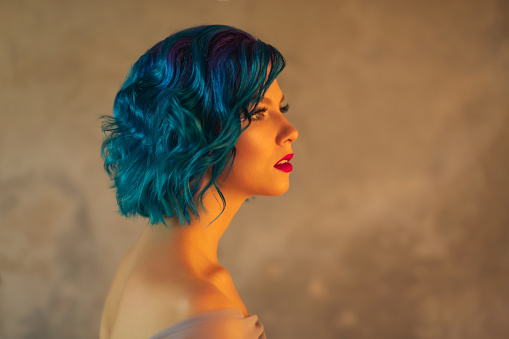 Girl with blue hair in studio on background of wall. Model with beauty makeup. Portrait. Red lips. Generation z