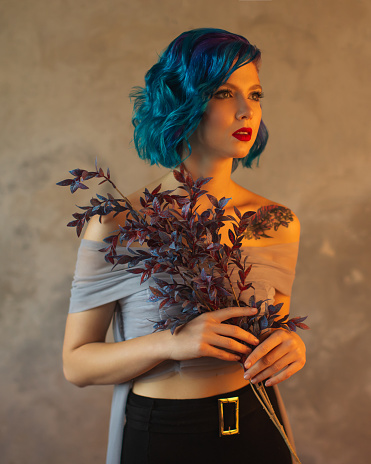 Girl with blue hair in studio on background of wall. Model with beauty makeup. Portrait. Red lips. Generation z
