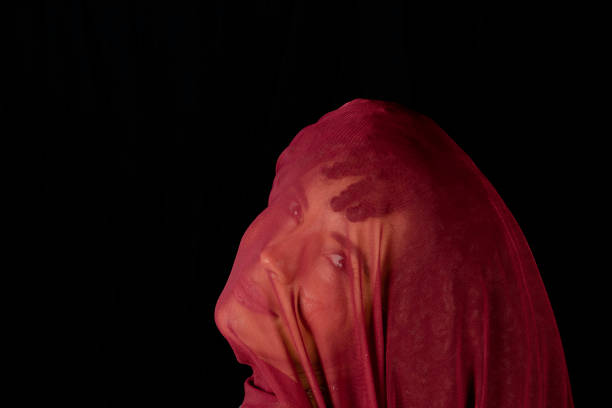 portrait of beautiful woman with thin cloth of dark red color on her face against black background. - brezilya lar stok fotoğraflar ve resimler