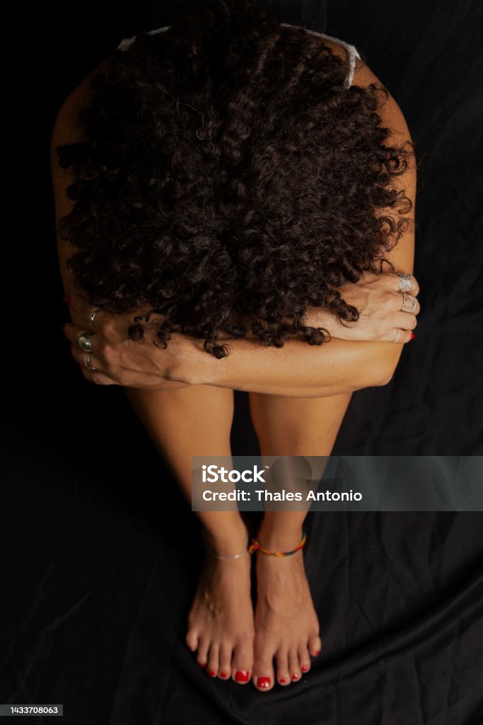Portrait of a woman sitting on the floor with her head on her knee against black background. - Royalty-free Kadın Stok görsel Portrait of a woman sitting on the floor with her head on her knee against black background. - Royalty-free Kadın Stok görsel