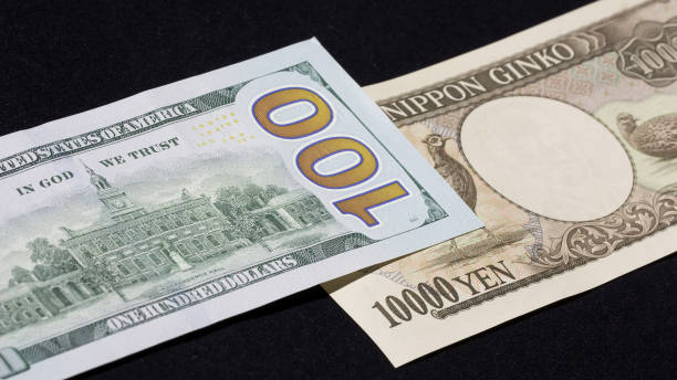 istock Back side of a US $100 bill and a 10,000 JPY bill stacked on solid black background 1433710830