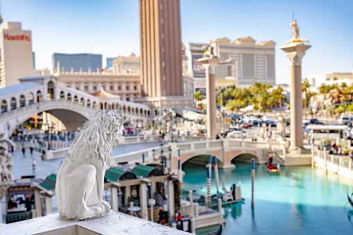 Las Vegas, NV - November 24, 2021: A gargoyle in focus overlooking the grounds of the famous Venetian Hotel and Casino, with the canal and gondolas in the distance.