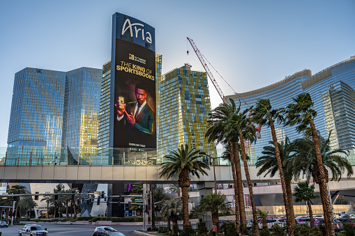 Las Vegas, NV - November 24, 2021: The Aria hotel and casino in view, with an ad for a sportsbook showing on the electronic billboard, beyond palm trees on Las Vegas Boulevard.