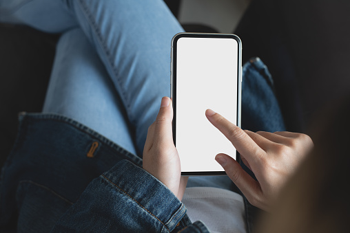 Woman using blank white screen mobile phone and finger touching on screen. Young woman pointing at mobile smartphone empty screen, mockup